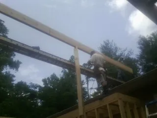 Carpenter setting a ridge beam over a new addition frame — Ice Dam Removal by Roofing Brothers in Enola