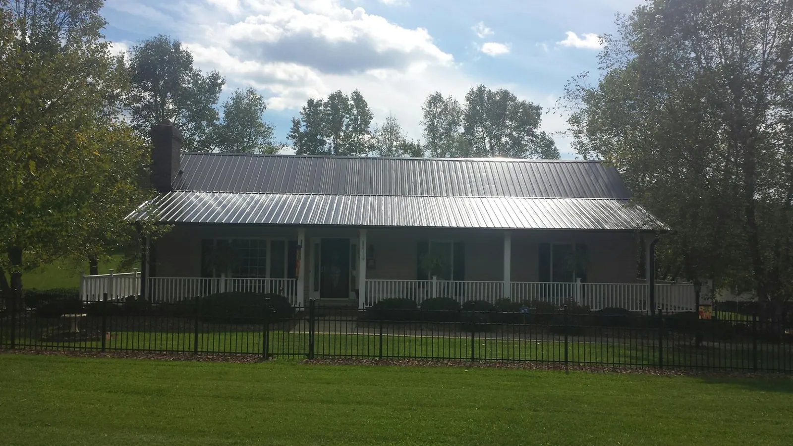 Gray metal roof on a brick ranch with a full width front porch — Gutter Guard Installation work by our crew in Enola