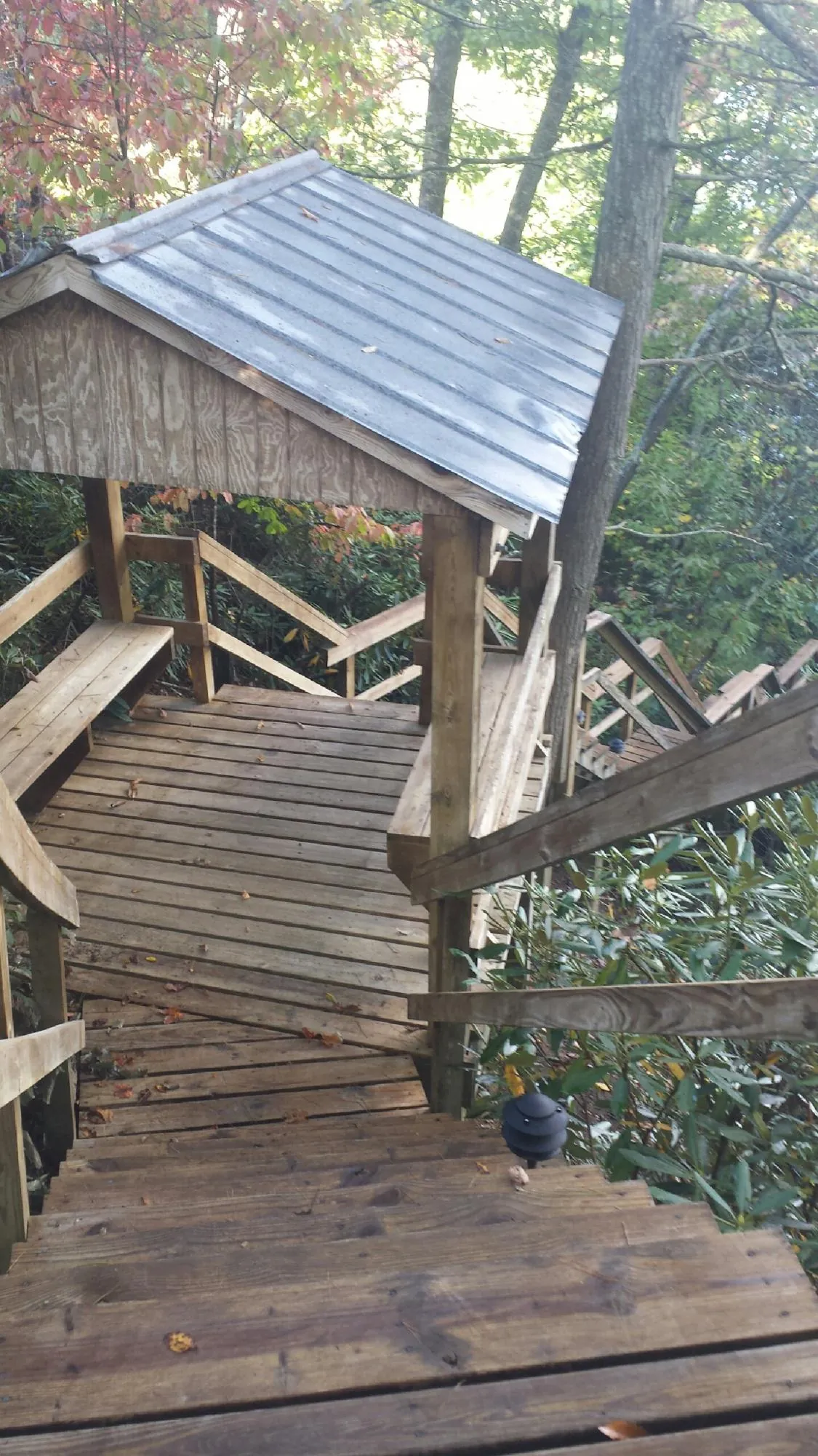 Metal roofed shelter over wooden steps on a wooded walkway — Skylight Repair & Installation work by our crew in Enola