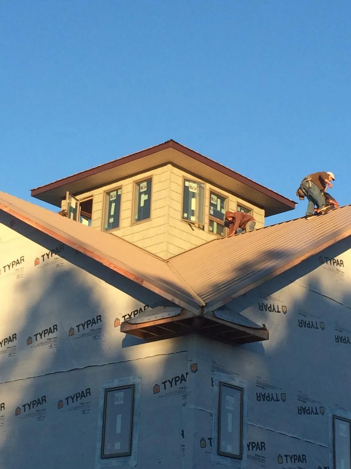 Roofers working around a rooftop cupola on a new metal roof at sunset — Roof Waterproofing in Enola by Roofing Brothers